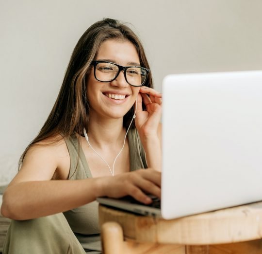 Freelancer woman at online meeting using laptop and headphones.